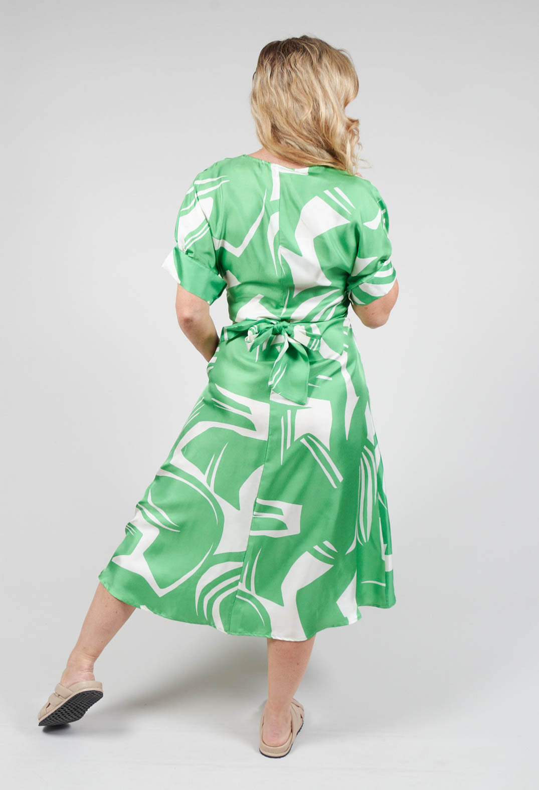 behind shot of Beatrice B wrap over silk dress in green with tie waist belt