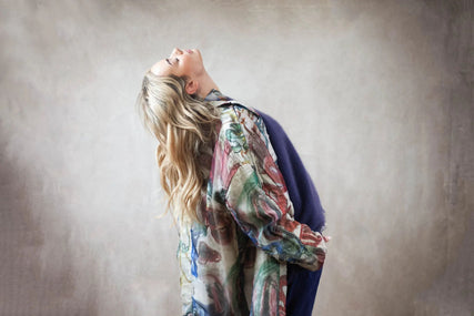 Woman wearing a colourful abstract-print coat layered over a purple outfit