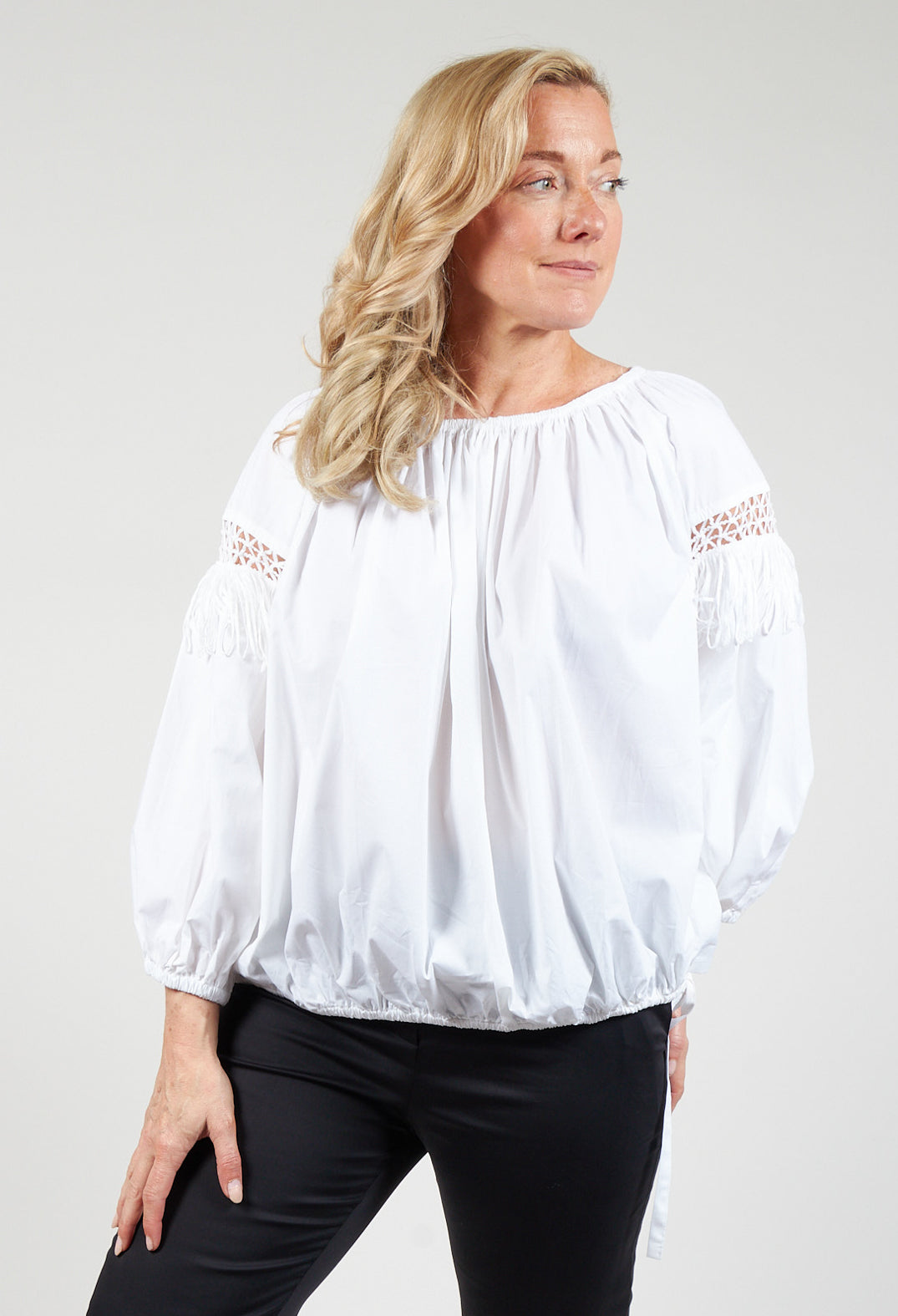lady wearing a fringe open work detail blouse in white