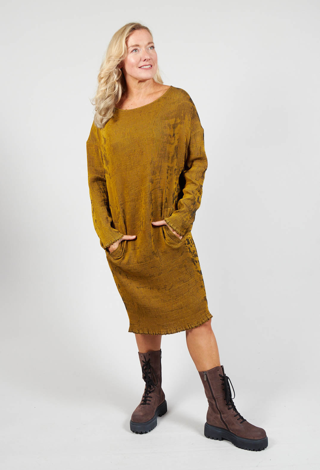 lady smiling wearing a long mustard dress with pockets and chunky boots