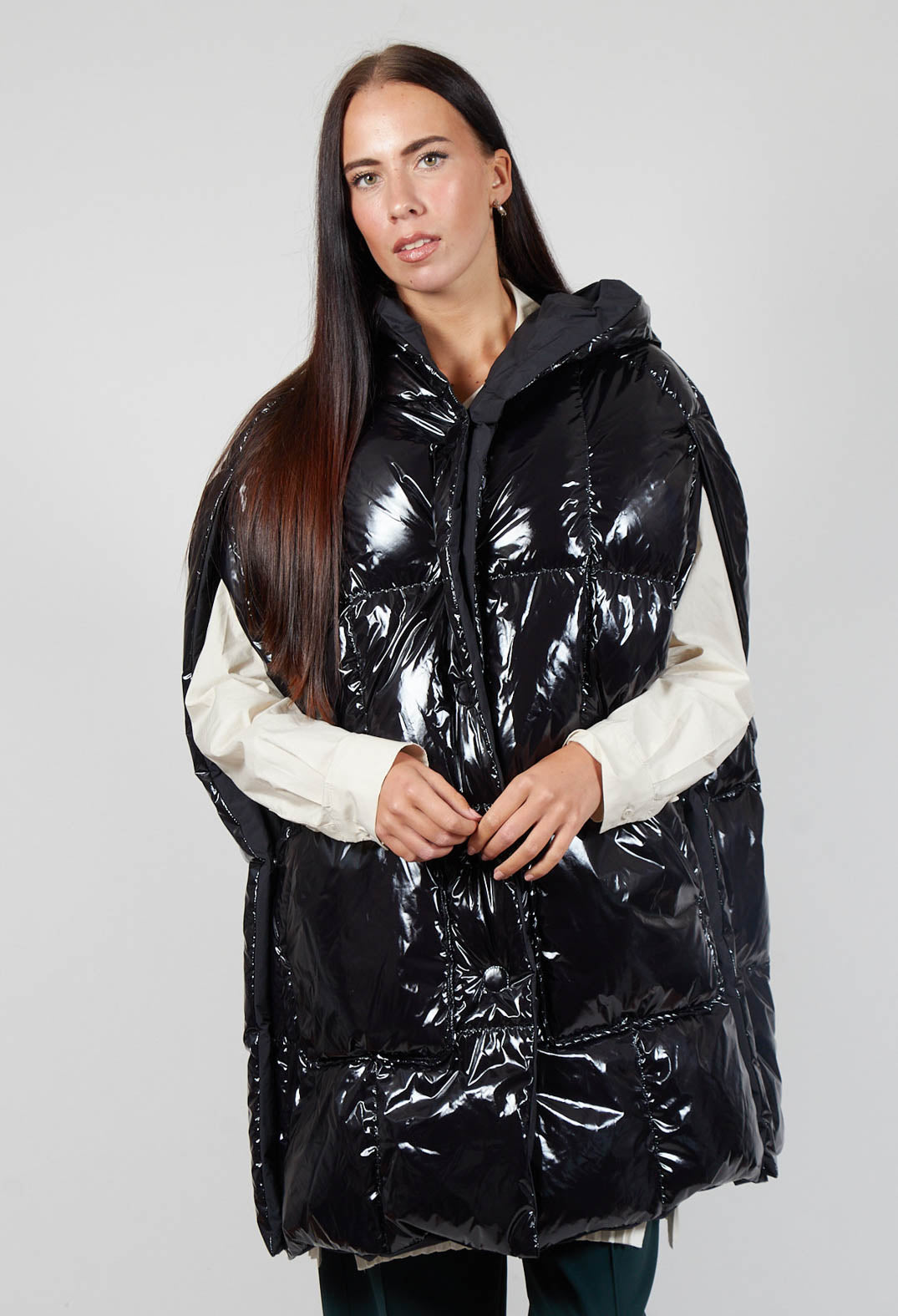 lady wearing a shiny black randy cape which has side pockets and button fastening