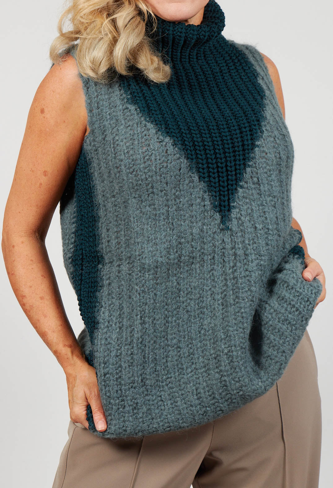 close up of ladies sleeveless knit jumper with a turtleneck in grey and dark green
