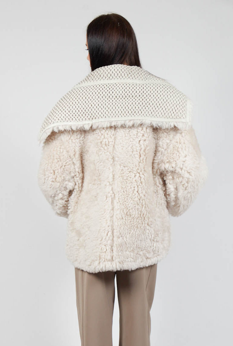 behind shot of lady wearing a cream siro jacket and light brown trousers