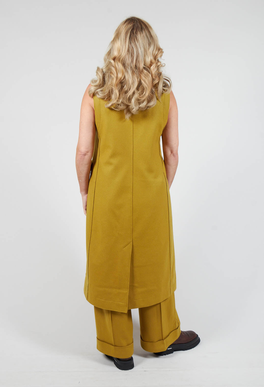 behind shot of lady wearing a campo vest in mustard and brown chunky boots