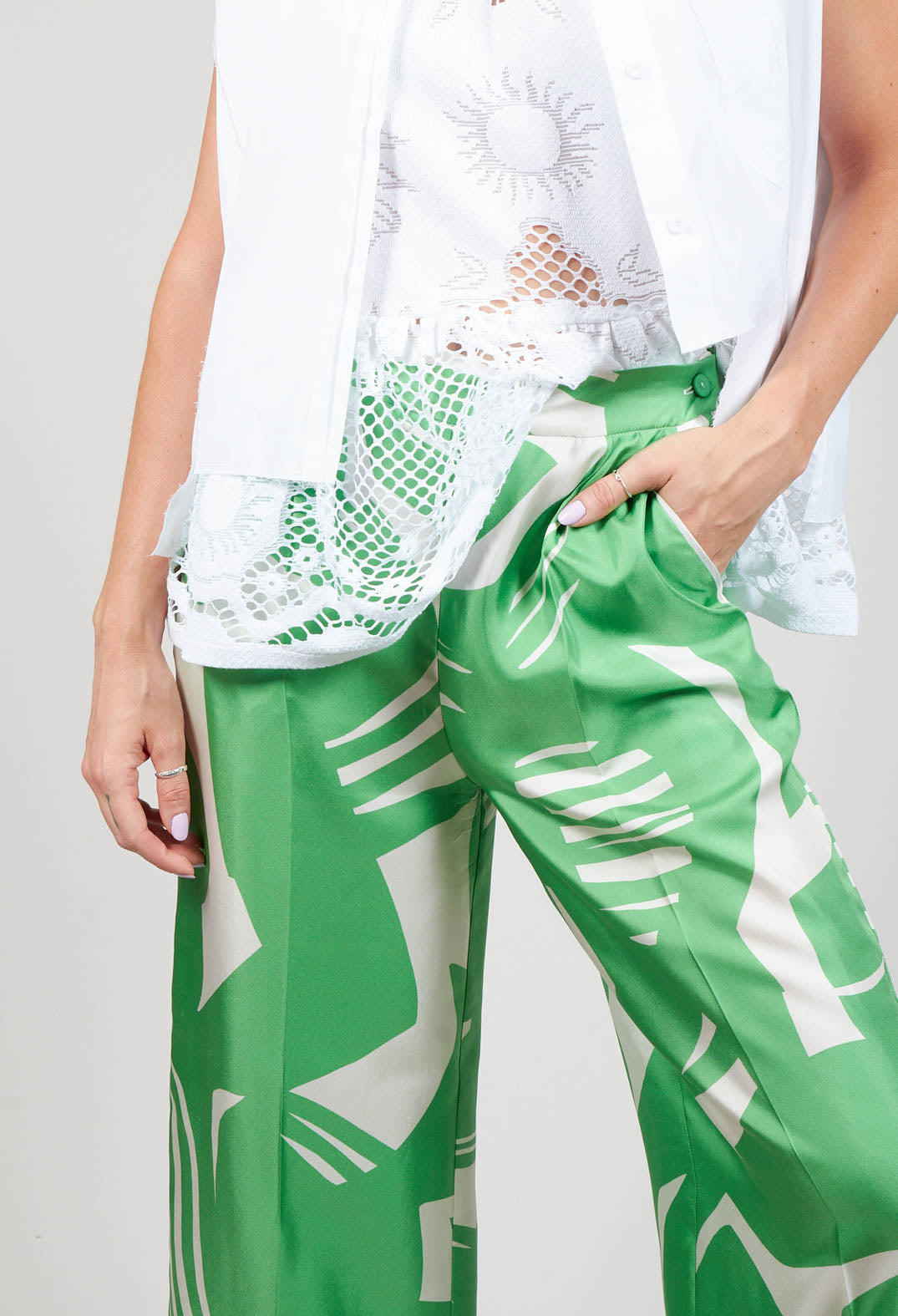 close up of green macro print silk trousers with button fastening and front pockets