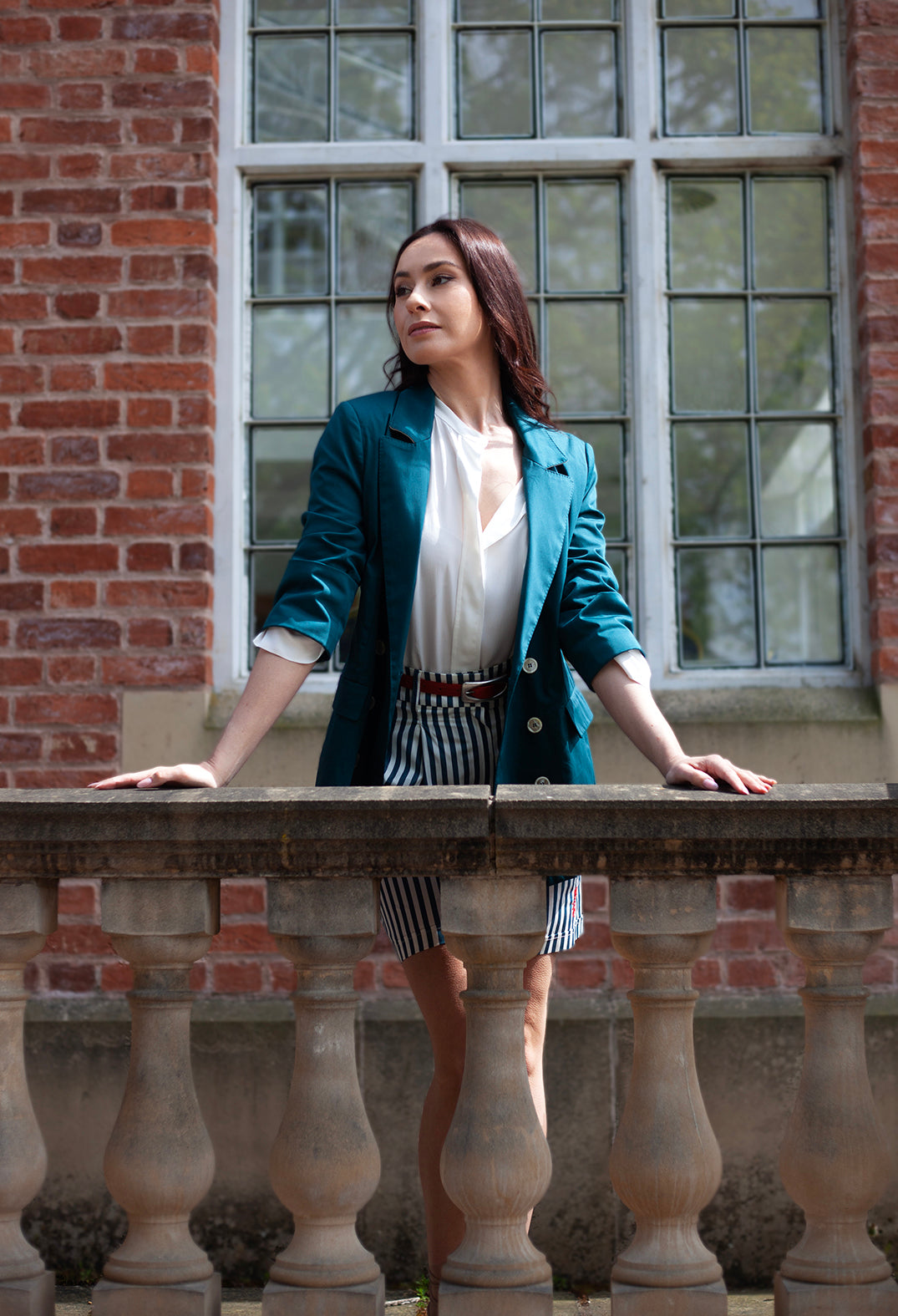lady leaning over a wall with tailored green jacket on
