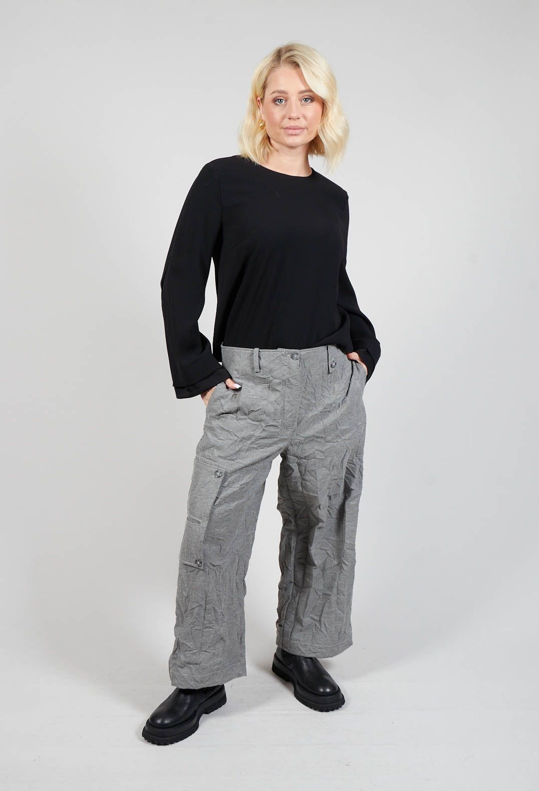 lady smiling wearing wide leg grey trousers with her hands in the side pockets