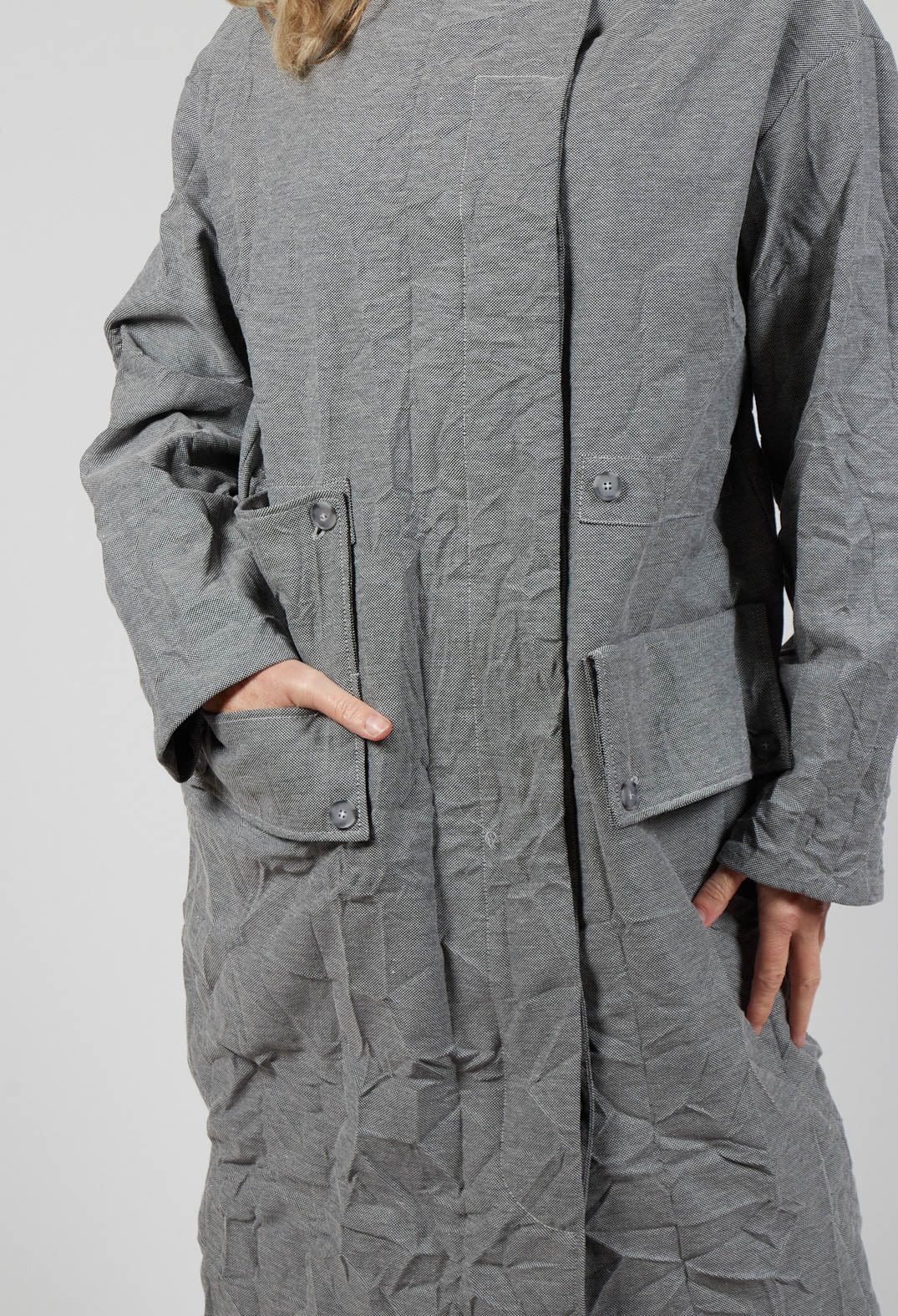 close up shot of a ladies light grey coat with button detail and side pockets