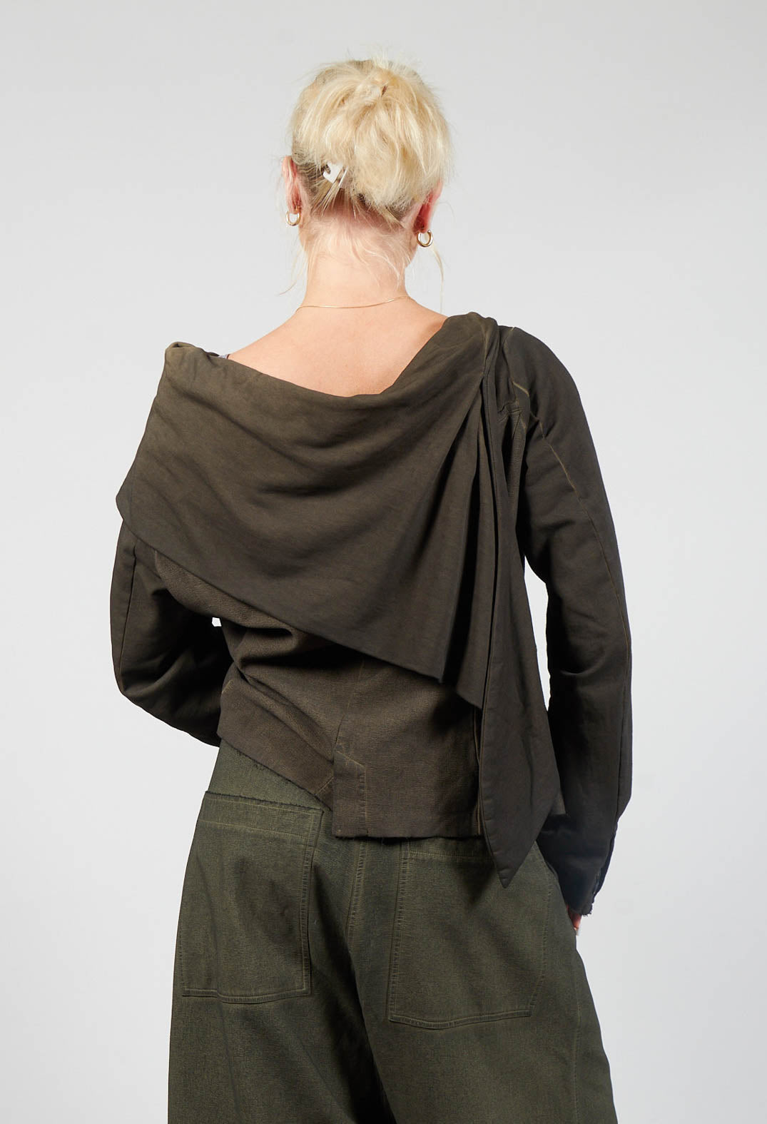 behind shot of a female wearing a khaki utility jacket with a scarf neck
