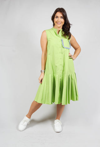 lady smiling wearing long sleeveless dress in green with pleated hem