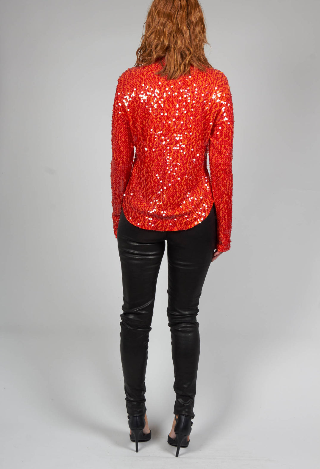 behind shot of lady wearing red long sleeve blouse with sequins