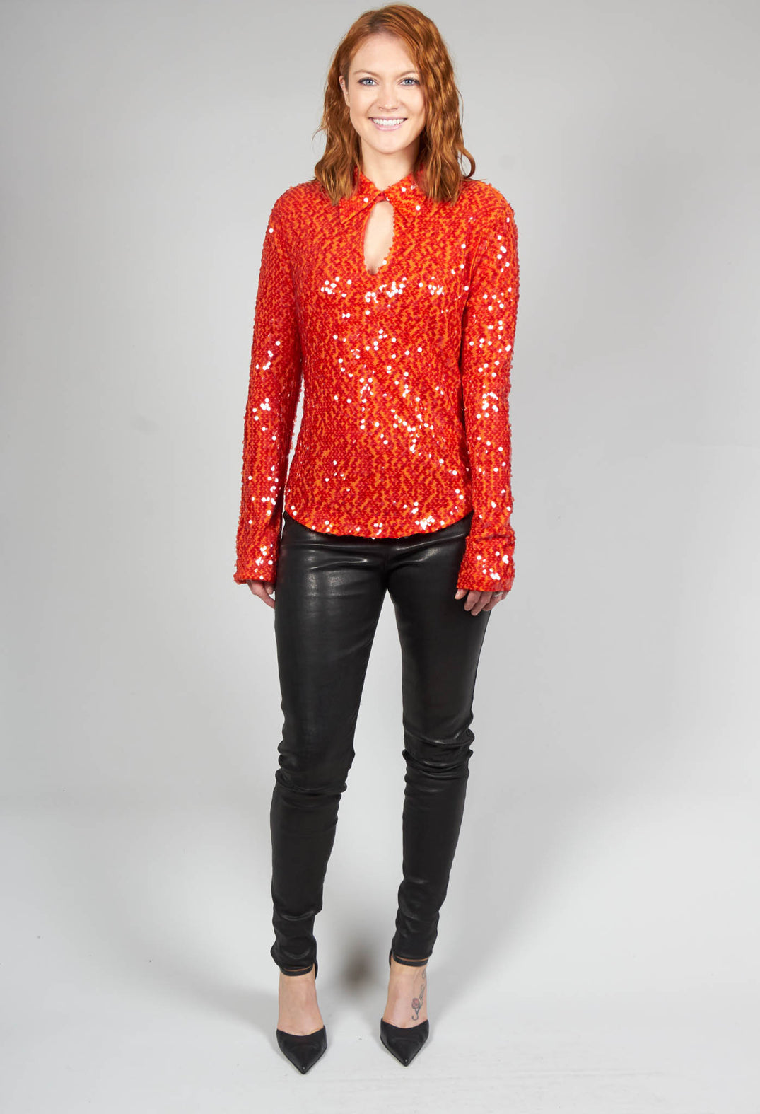 happy lady wearing a red long sleeve blouse with sequin detail