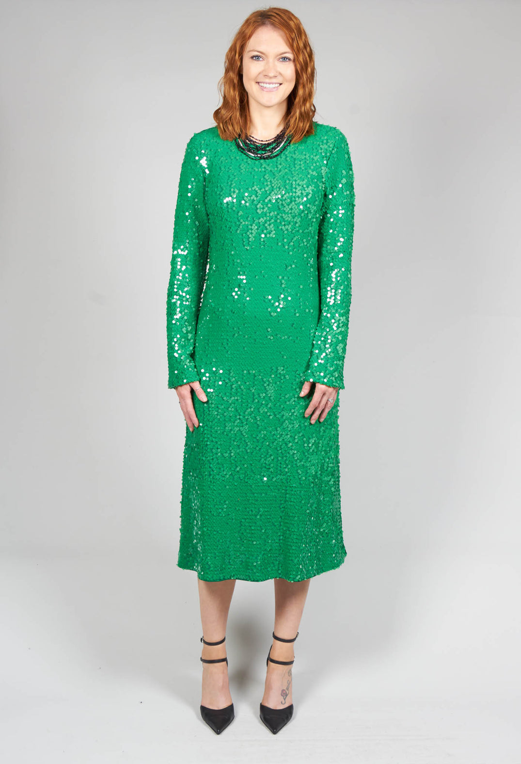 lady smiling wearing a long green sequin dress