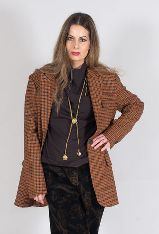lady wearing a houndstooth jacket in orange print featuring pockets and long collar